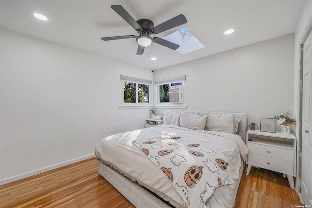 bedroom with ceiling fan, a closet, a wall unit AC, and light hardwood / wood-style flooring