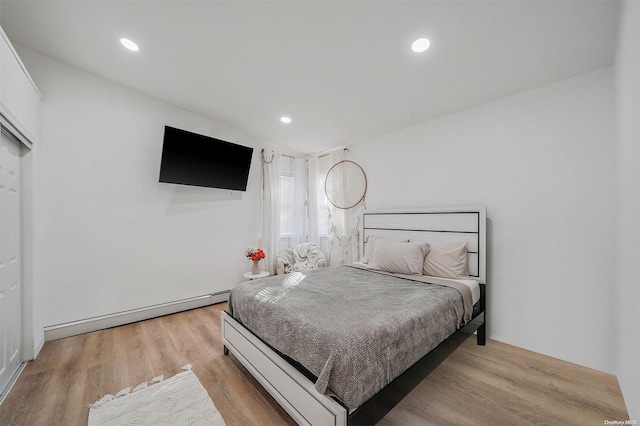 bedroom featuring light hardwood / wood-style floors and a baseboard heating unit