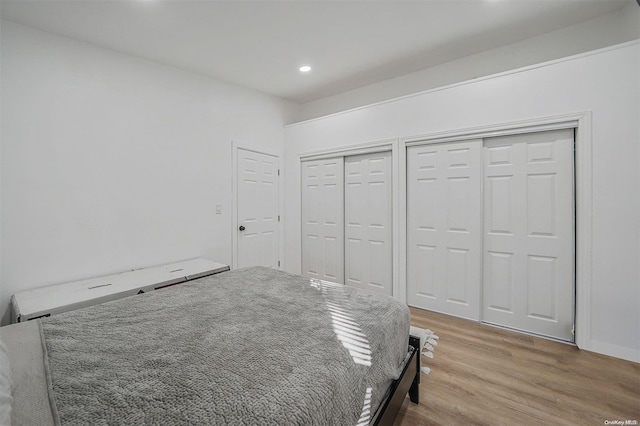 unfurnished bedroom featuring light hardwood / wood-style floors and multiple closets