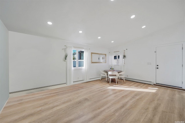 interior space with baseboard heating, light hardwood / wood-style flooring, and vaulted ceiling