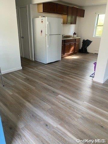 kitchen featuring dark brown cabinets, white refrigerator, and light hardwood / wood-style flooring