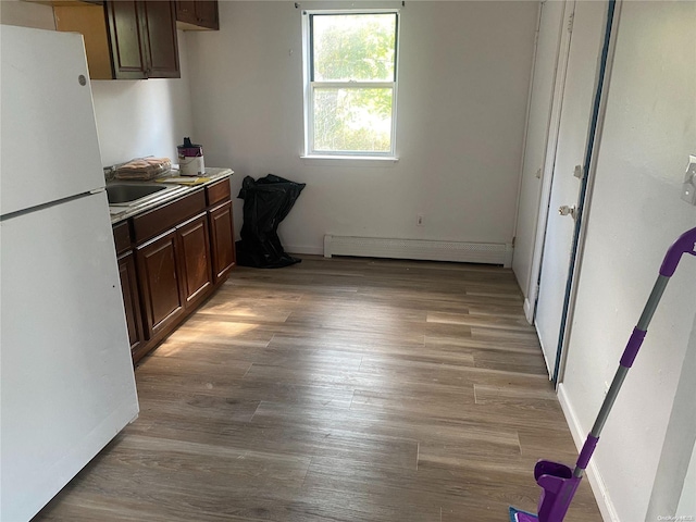 kitchen featuring dark brown cabinets, white refrigerator, light wood-type flooring, and a baseboard radiator