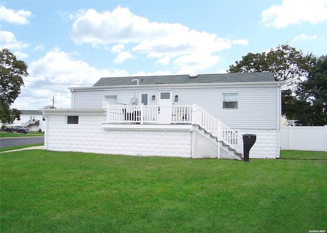 back of property featuring a deck and a lawn