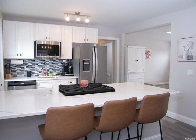 kitchen with a breakfast bar, sink, white cabinetry, and stainless steel appliances