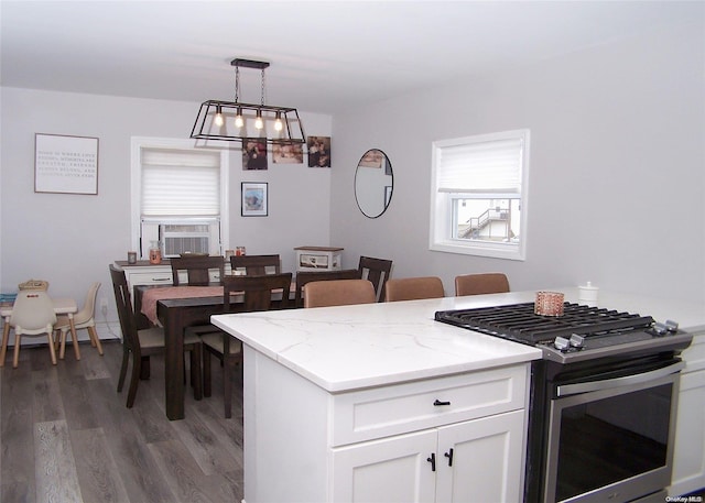 kitchen featuring light stone countertops, stainless steel gas range, decorative light fixtures, dark hardwood / wood-style floors, and white cabinetry