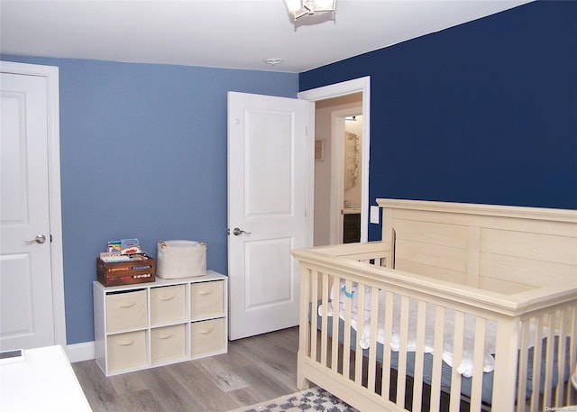 bedroom featuring light hardwood / wood-style flooring and a nursery area