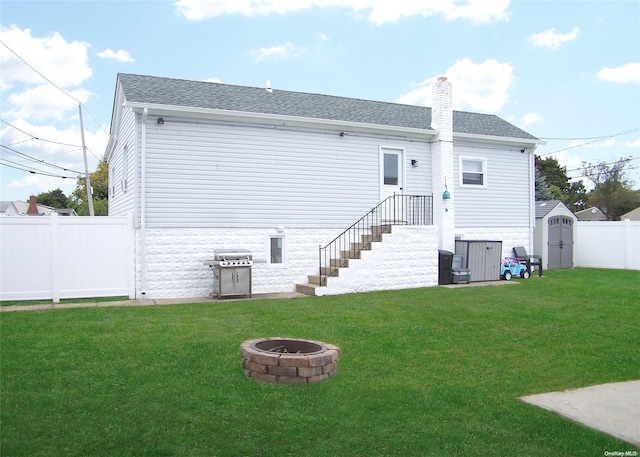 rear view of house with a lawn, a fire pit, and a storage shed