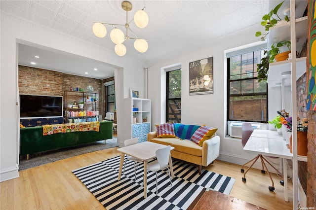 living room featuring cooling unit, brick wall, a notable chandelier, and light wood-type flooring