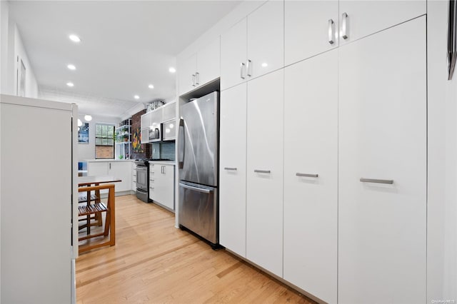 kitchen with tasteful backsplash, white cabinetry, light hardwood / wood-style flooring, and stainless steel appliances