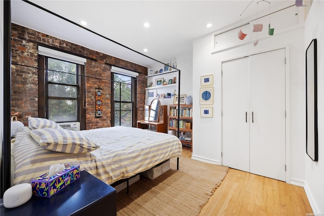 bedroom with wood-type flooring and brick wall