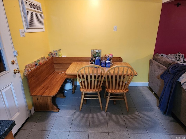 dining area with a wall mounted AC and dark tile patterned floors