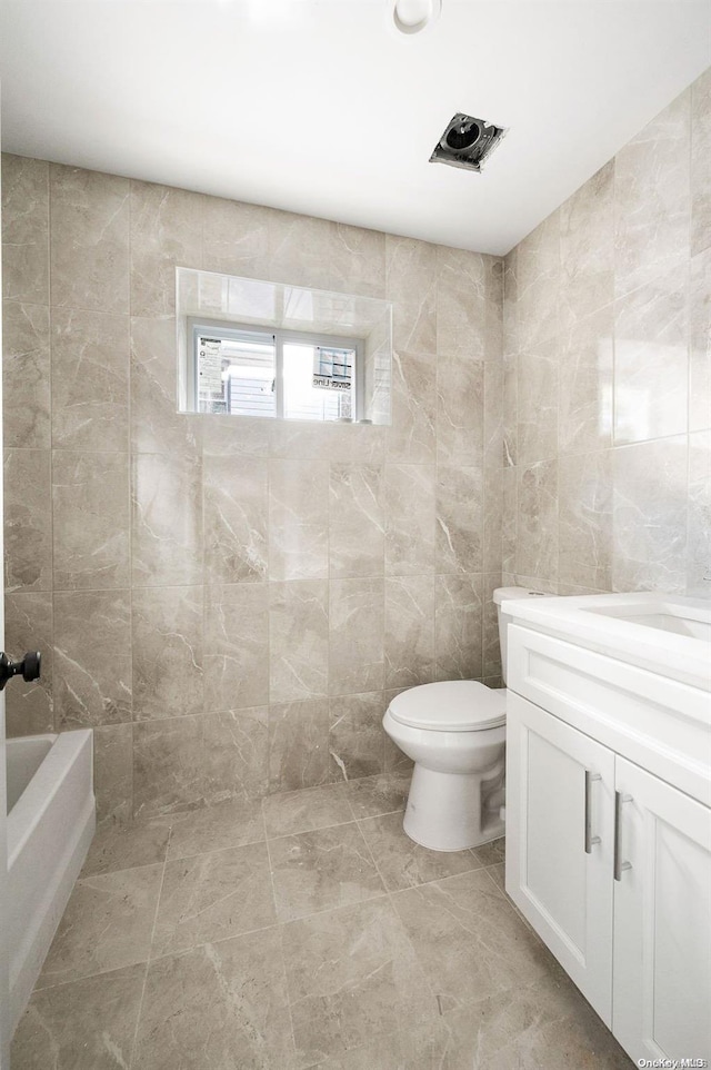 bathroom featuring vanity, toilet, and tile walls