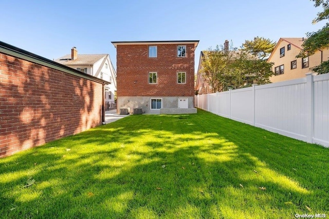 rear view of house featuring a lawn and central air condition unit