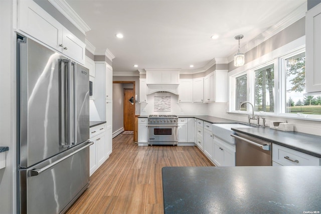 kitchen featuring hanging light fixtures, wood-type flooring, high quality appliances, white cabinets, and ornamental molding