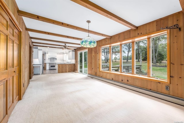 unfurnished living room with wood walls, light carpet, ceiling fan, a baseboard radiator, and beamed ceiling