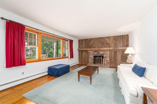 living room with hardwood / wood-style floors, wood walls, a wood stove, and a baseboard radiator