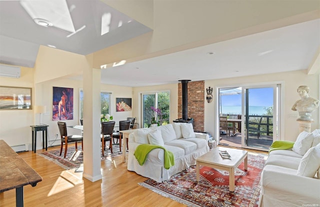 living room featuring plenty of natural light, light wood-type flooring, a wood stove, and a wall unit AC