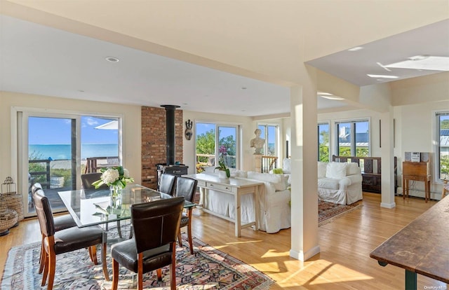 dining room with light wood-type flooring, a water view, and a wood stove