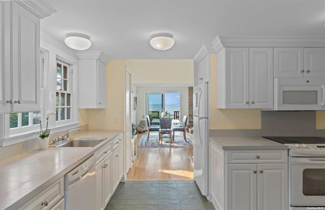 kitchen featuring white cabinetry, a wealth of natural light, sink, and white appliances