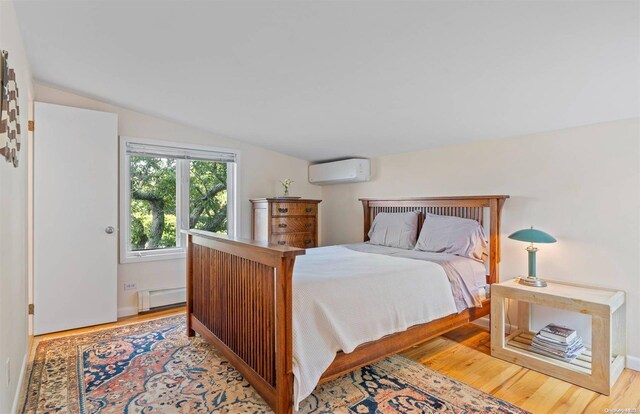 bedroom with lofted ceiling, light hardwood / wood-style flooring, a wall unit AC, and a baseboard heating unit