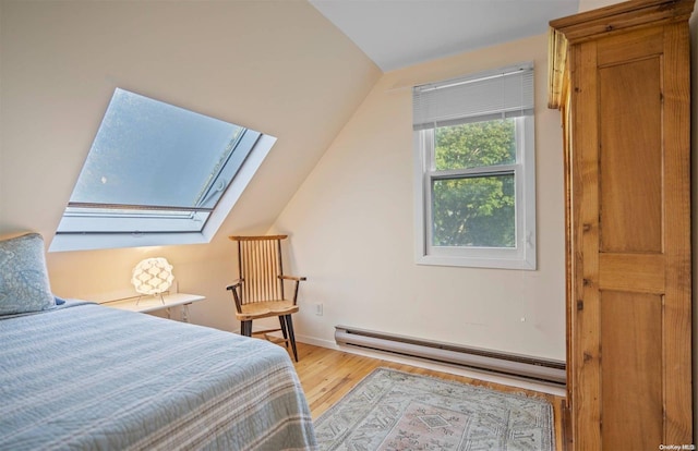 bedroom featuring hardwood / wood-style floors, lofted ceiling with skylight, and a baseboard heating unit