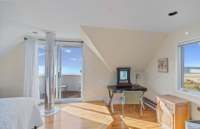 bedroom featuring a baseboard heating unit, lofted ceiling, and light wood-type flooring