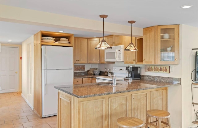 kitchen featuring white appliances, a kitchen breakfast bar, dark stone countertops, decorative light fixtures, and kitchen peninsula