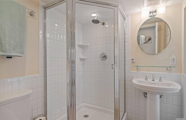 bathroom featuring walk in shower, tile walls, and toilet