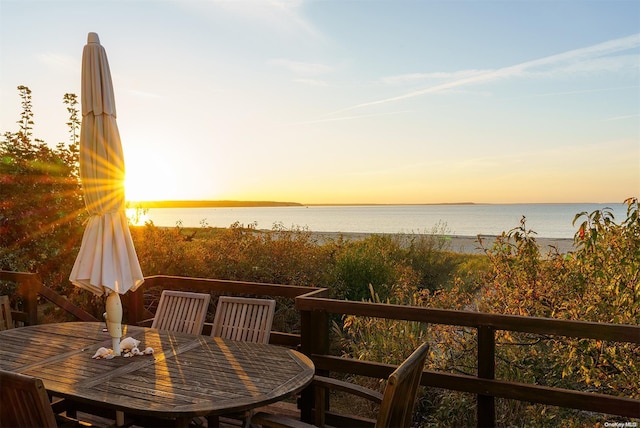 balcony at dusk featuring a water view