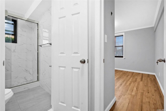 bathroom featuring toilet, crown molding, a shower with door, and hardwood / wood-style flooring