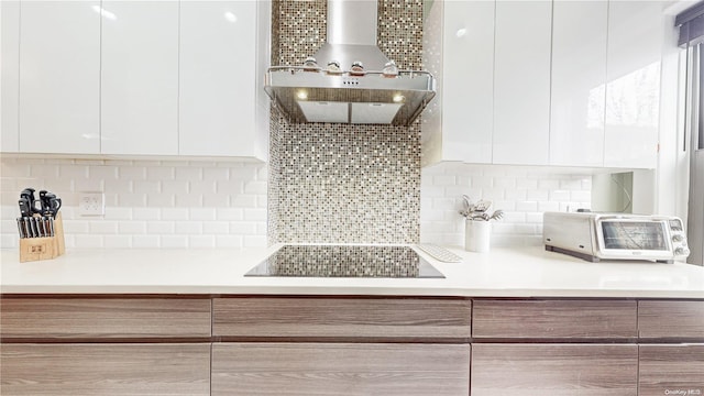 kitchen featuring backsplash, white cabinetry, black electric stovetop, and wall chimney exhaust hood