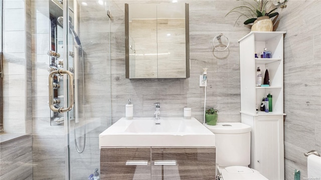 bathroom with vanity, toilet, tile walls, and a shower with shower door