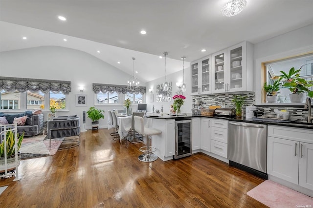 kitchen with pendant lighting, lofted ceiling, wine cooler, stainless steel dishwasher, and white cabinetry