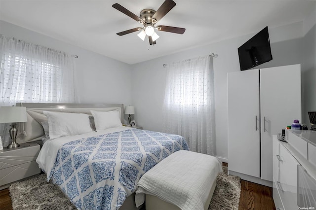 bedroom featuring dark hardwood / wood-style floors, multiple windows, and ceiling fan