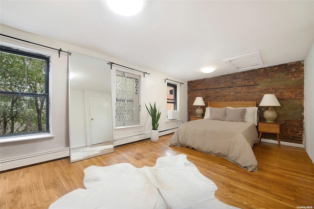 bedroom featuring a baseboard radiator, light hardwood / wood-style flooring, and multiple windows