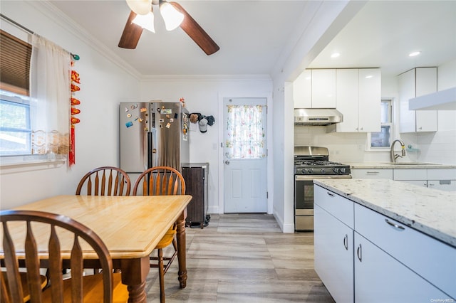 kitchen featuring light stone countertops, appliances with stainless steel finishes, tasteful backsplash, ornamental molding, and white cabinetry