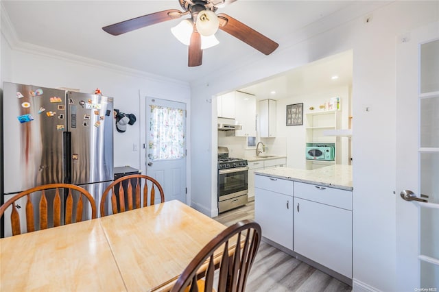 kitchen with backsplash, white cabinets, appliances with stainless steel finishes, light hardwood / wood-style floors, and light stone counters