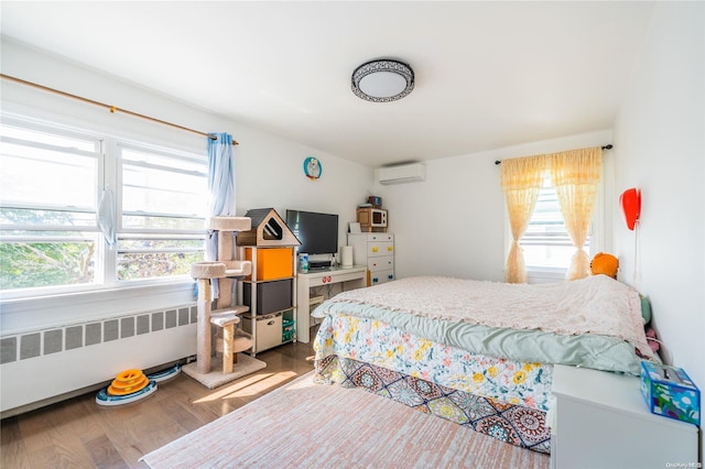 bedroom featuring radiator heating unit, hardwood / wood-style flooring, and a wall mounted AC