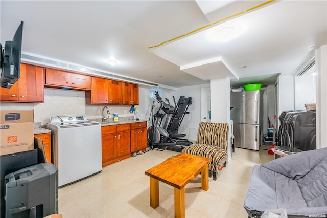 kitchen featuring decorative backsplash, stainless steel fridge, washer / dryer, and sink