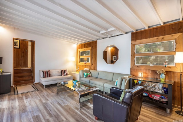 living room with beam ceiling, wood walls, and light hardwood / wood-style floors