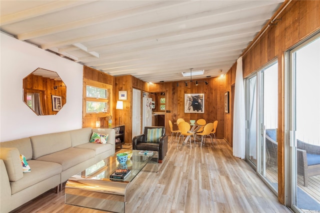 living room featuring wood walls, beamed ceiling, and light hardwood / wood-style floors