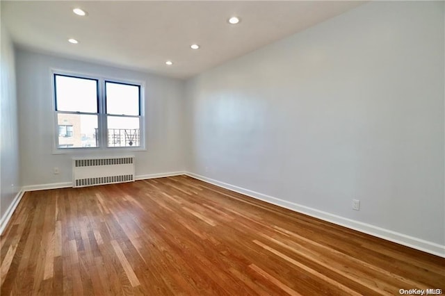 spare room with wood-type flooring and radiator heating unit