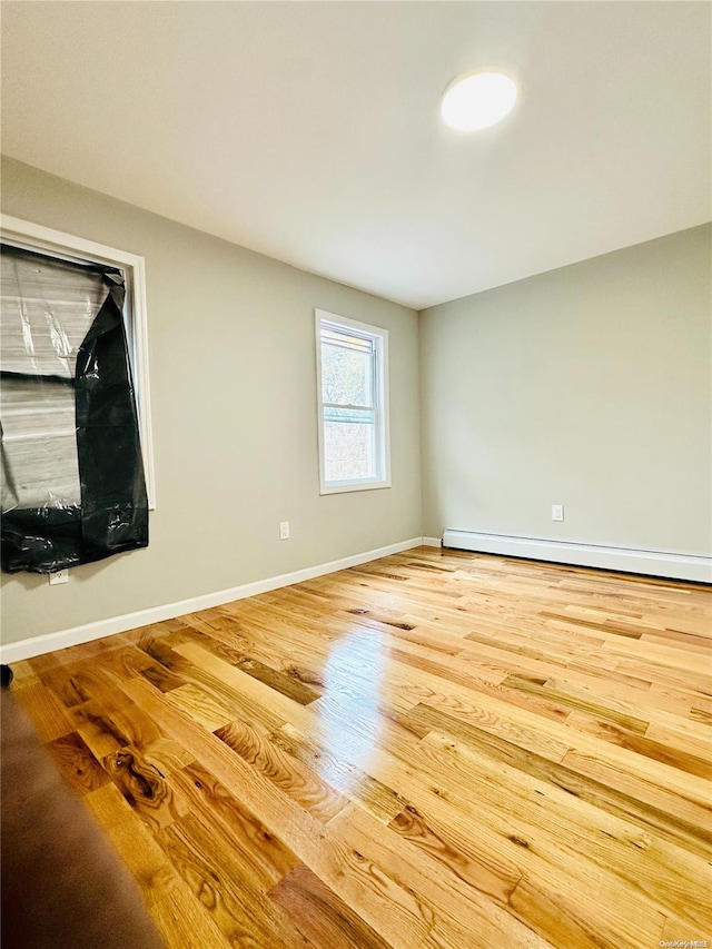 unfurnished living room with hardwood / wood-style flooring and baseboard heating