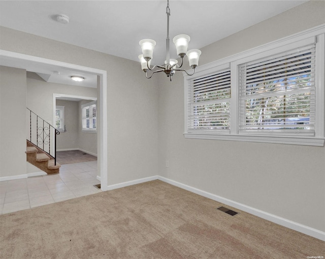 carpeted empty room with a chandelier and plenty of natural light