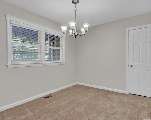 spare room featuring a notable chandelier and light carpet