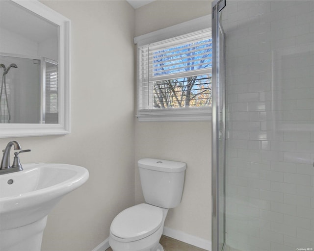 bathroom featuring toilet, a shower with shower door, and sink