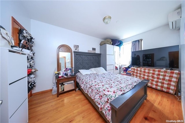 bedroom featuring light hardwood / wood-style floors and a wall mounted air conditioner