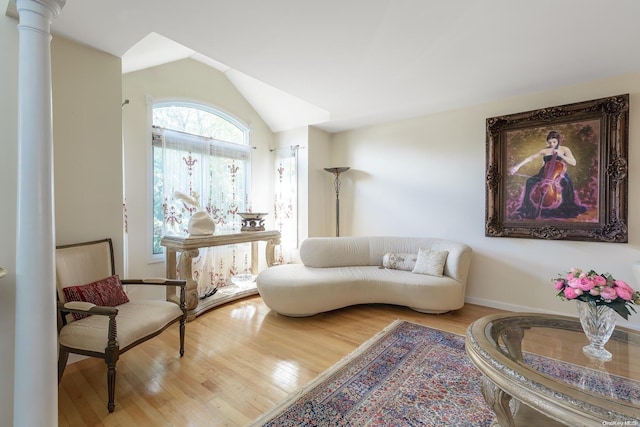 sitting room featuring decorative columns, light hardwood / wood-style flooring, and vaulted ceiling