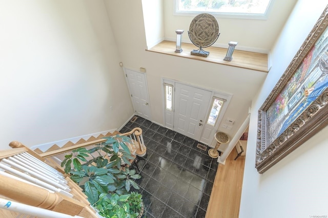 foyer entrance featuring wood-type flooring and a towering ceiling