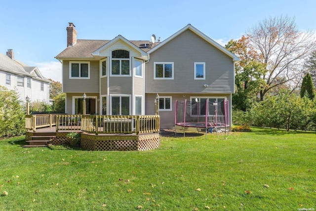 back of house featuring a yard, a deck, and a trampoline